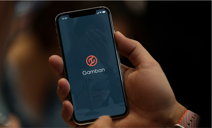 A person holding an iPhone in their hand, with the Gamban app running