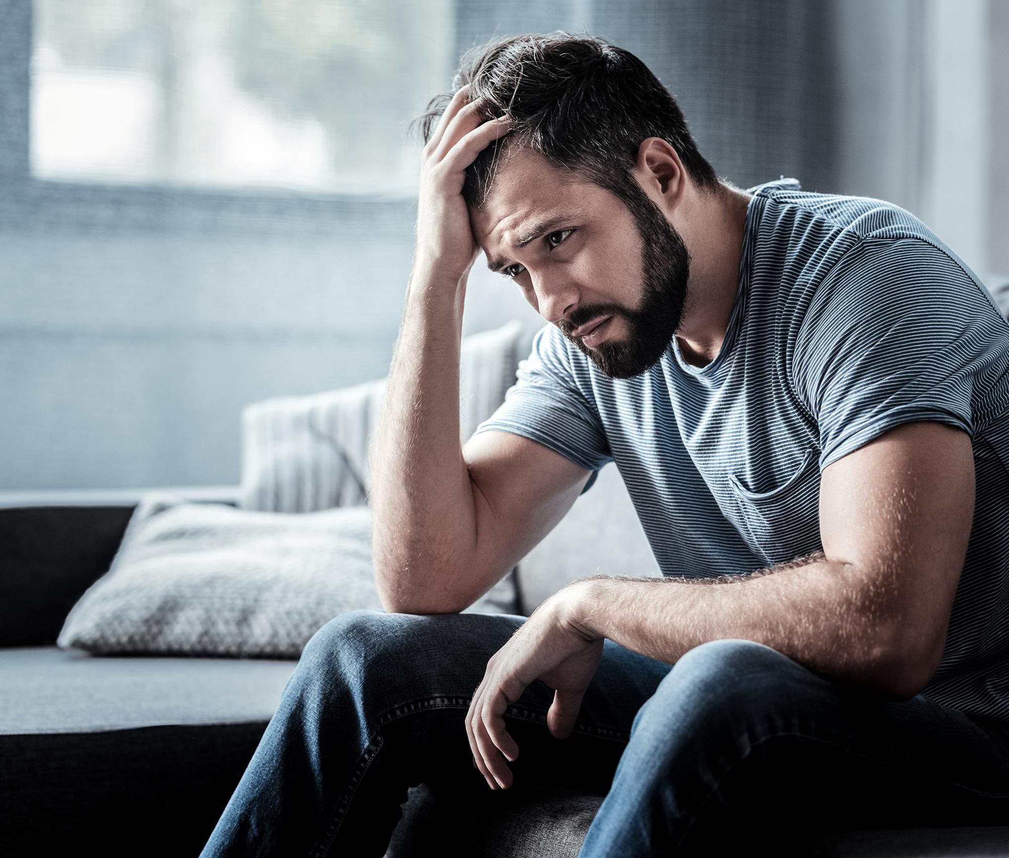 An upset looking man holding his head